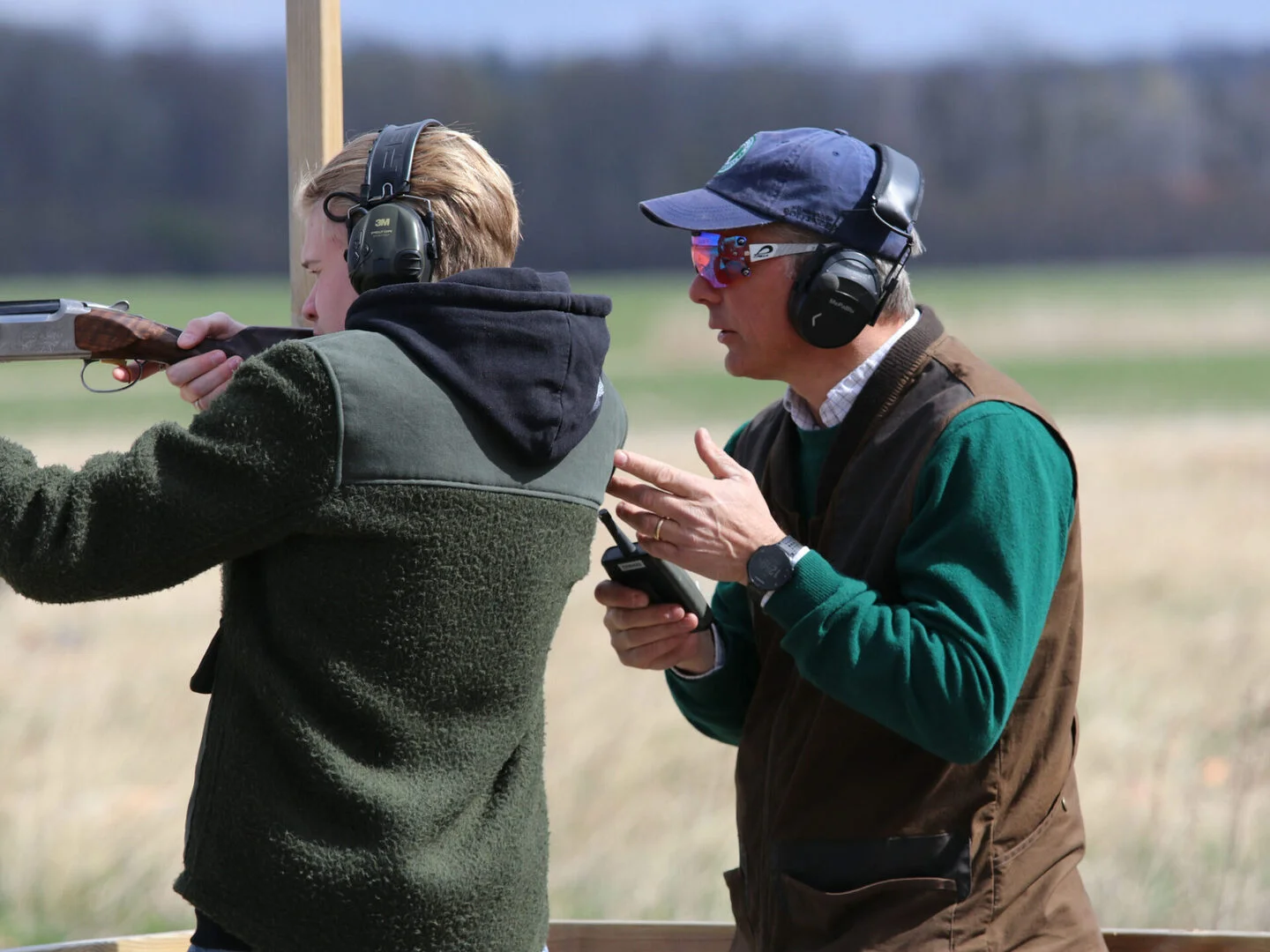 intruktör brevid kursdeltagare för skytteträning